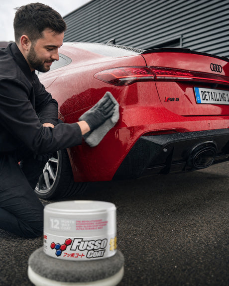 Daniel poliert das frisch gewachste Heck eines roten Audi RS 5 mit Mikrofasertuch aus, davor die Soft99 Fusso Coat Wachsdose.