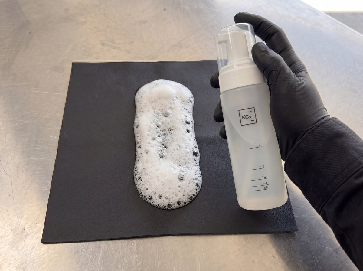 Bubbliger Schaum aus Koch-Chemie Foamer Bottle wird auf schwarzes Lederbezug-Sample im Detailing1 Warehouse aufgepumpt
