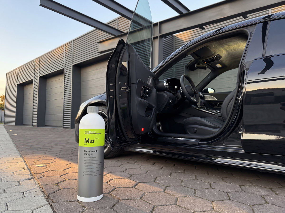 Koch-Chemie Mzr 1L Flasche neben offener Tür eines schwarzen Mercedes-AMG GT in der Warehouse-Werkstatt