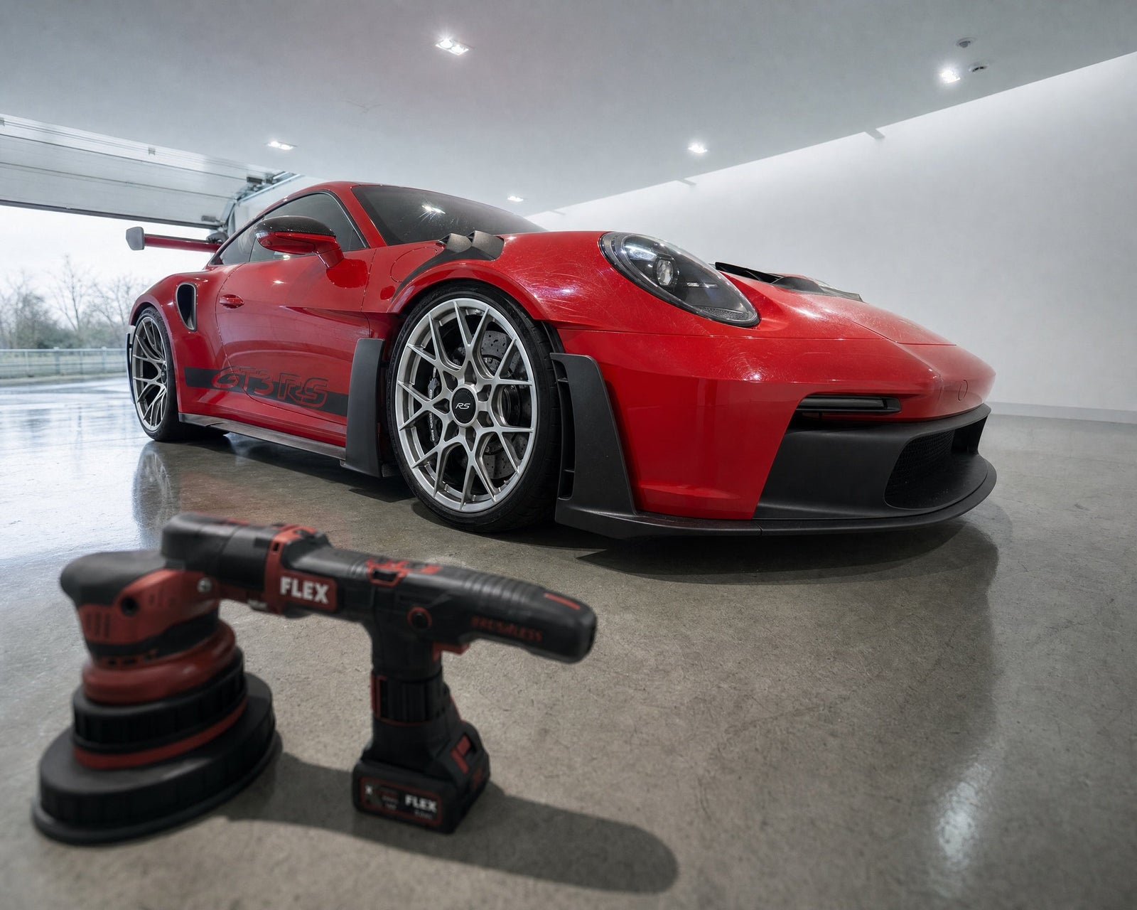 Detailing1 FLEX Exzenter- und Rotationspolierer liegen vor einem roten Porsche 911 GT3 RS in der Halle