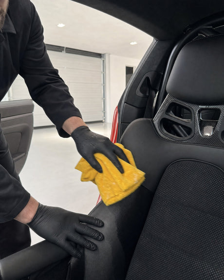 Daniel reinigt mit Mikrofasertuch die Ledersitzwange im roten Porsche 911 GT3 RS, eine Zone schon tiefschwarz, daneben grau.