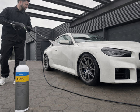 Daniel spült mit dem Hochdruckreiniger die Flanke eines weißen BMW M2 ab, die Koch-Chemie Gentle Snow Foam Flasche steht auf 